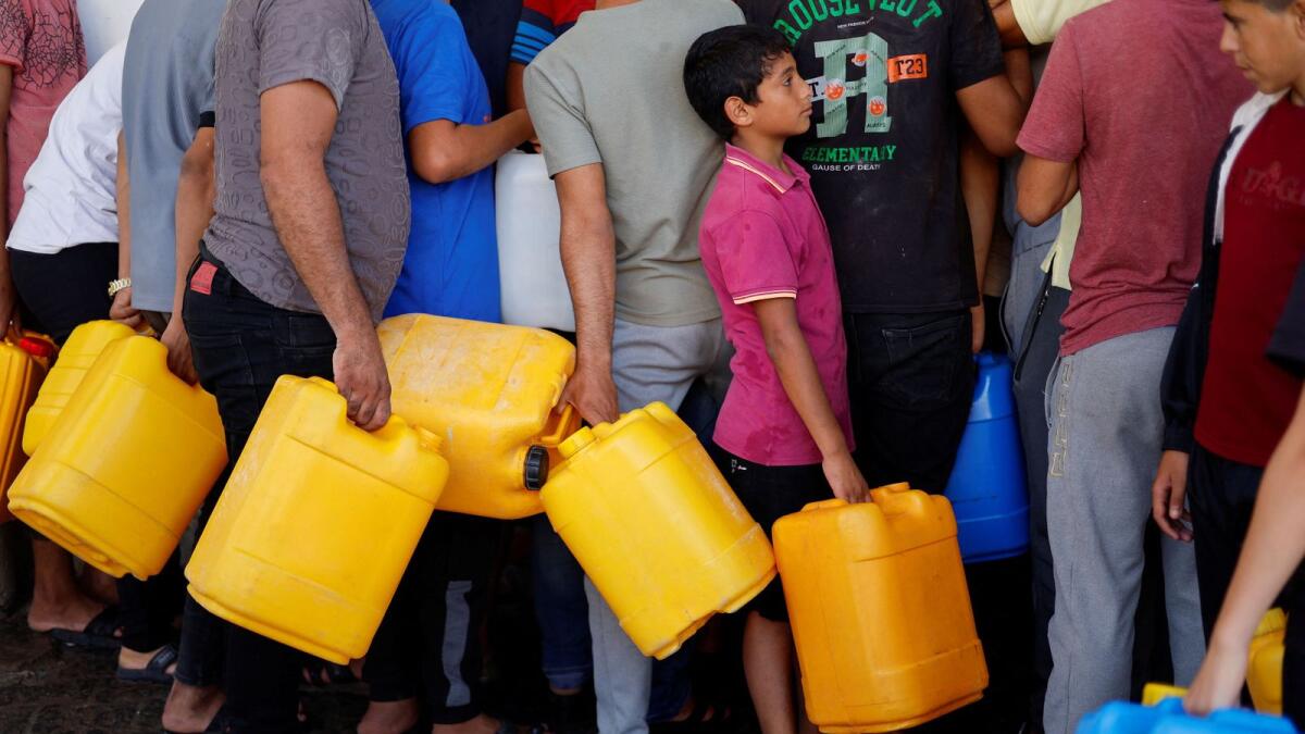 Palestinians gather to collect water in Khan Younis in the southern Gaza Strip on Sunday. — Reuters