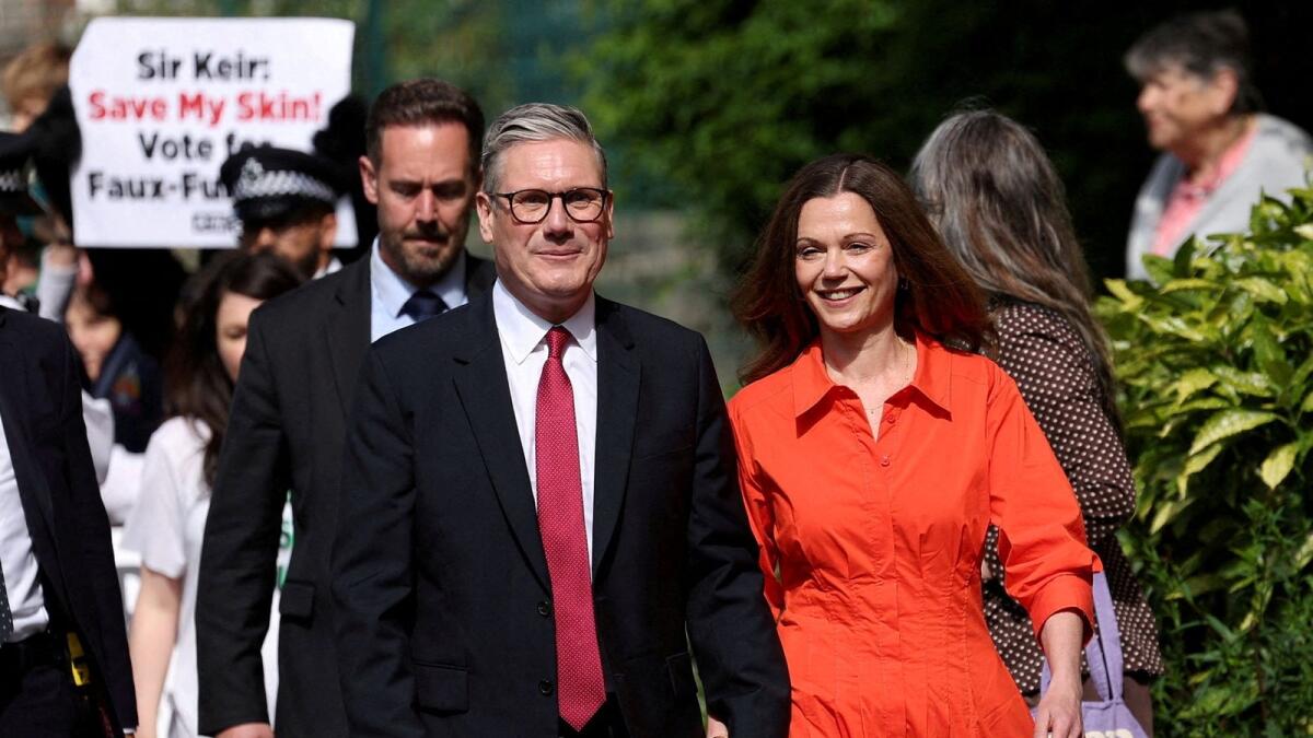 Britain's opposition Labour Party leader Keir Starmer and his wife Victoria Starmer walk outside a polling station during the general election in London on Thursday. — Reuters