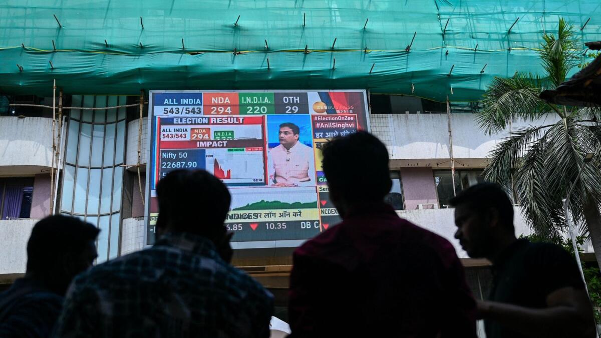Pedestrians watch share prices on a digital broadcast outside the Bombay Stock Exchange on Tuesday. — AFP