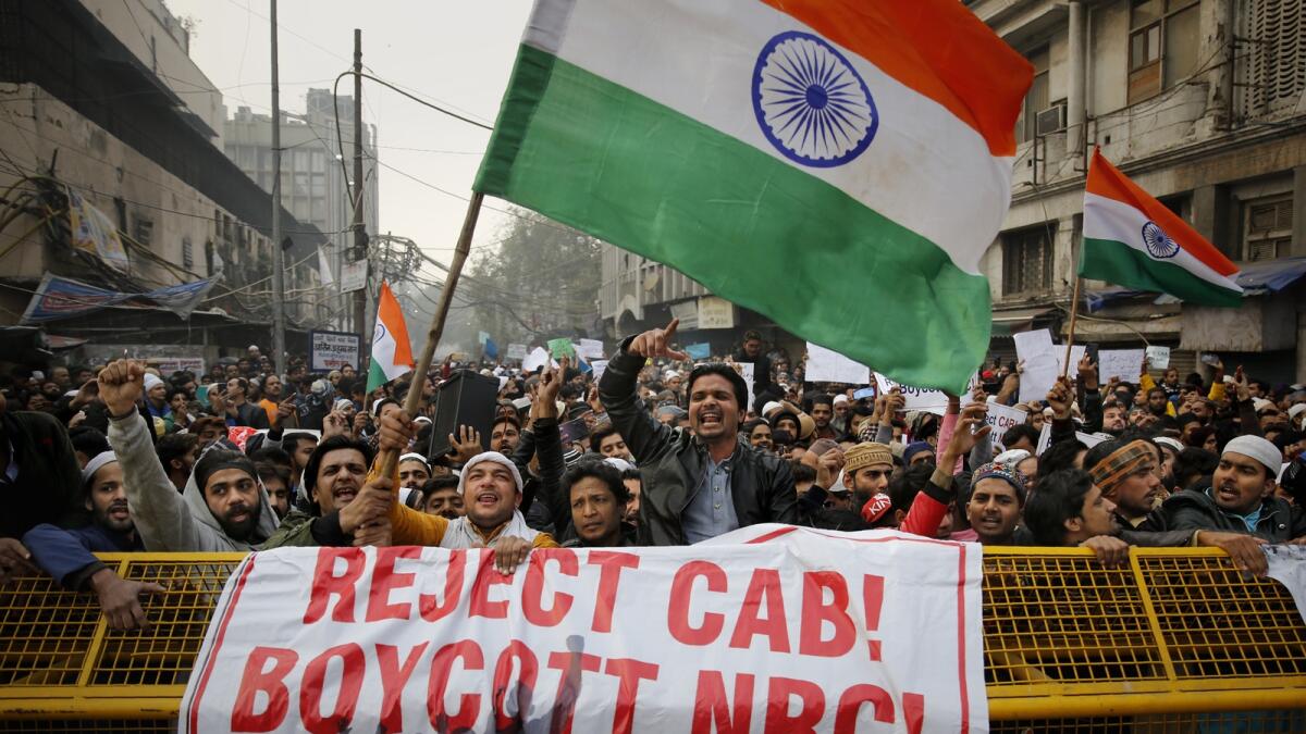 Indians wave national flags and shout slogans behind a police barricade during a protest against the Citizenship Amendment Act in New Delhi in 2019. — AP file