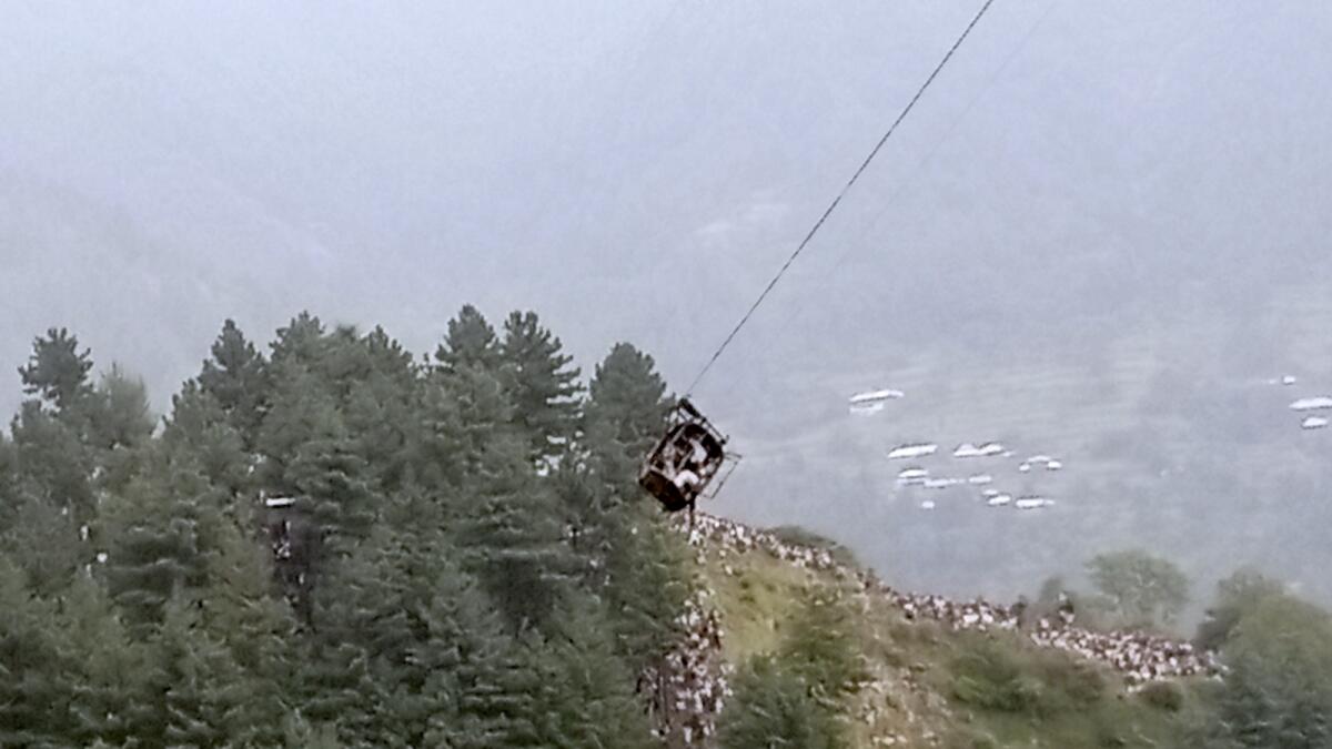 A cable car carrying eight people dangles hundreds of metres above the ground. — AP
