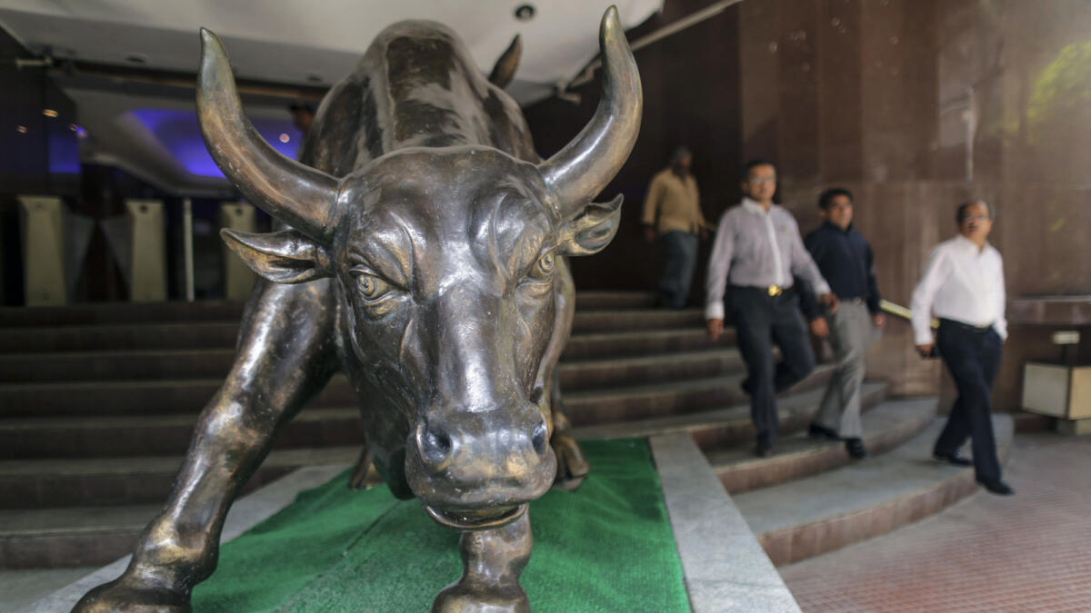 Men walk past a bronze bull statue at the entrance to the Bombay Stock Exchange (BSE) building in Mumbai. — File photo