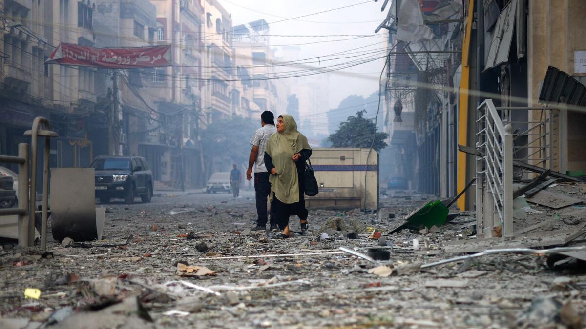 Photo: A Palestinian woman looks on as she walks on a debris-strewn street near the Watan Tower (Reuters)