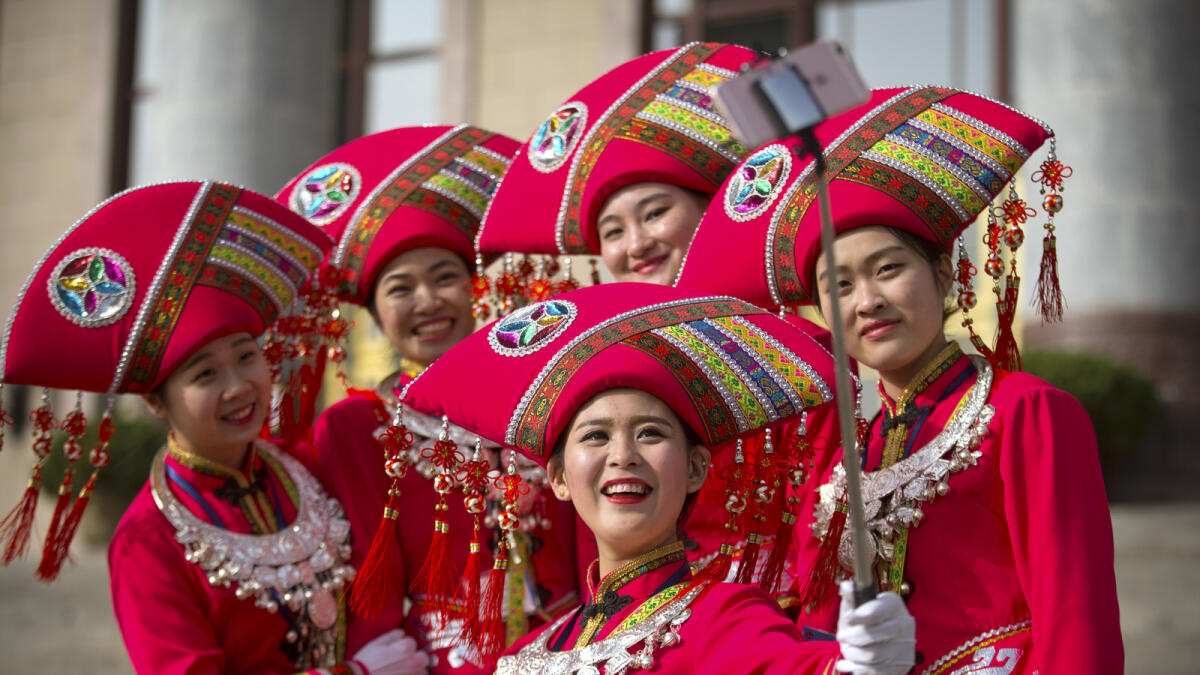 Hostesses, who facilitated the arrival of delegates by bus, pose for a selfie on the steps of the Great Hall of the People during the opening session of China's annual National People's Congress (NPC) in Beijing, Saturday, March 5, 2016. (AP Photo/Mark Schiefelbein)