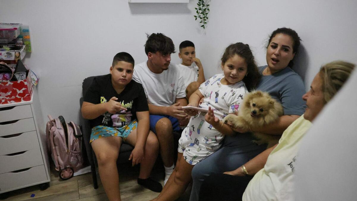 An Israeli family take shelter in a basement in the southern city of Ashkelon as sirens wail while barrages of rockets are fired from the Gaza Strip into Israel on October 7, 2023. AFP