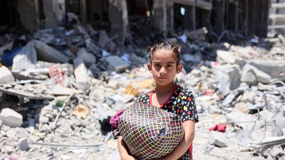 A Palestinian girl carries some salvaged belongings in the Jabalia refugee camp in the northern Gaza Strip after she returned briefly with others who sought to check on their homes. — Photo: AFP