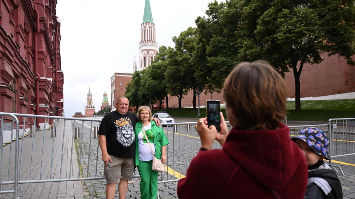 A couple standing in front of metal barriers pose for a photo in Moscow's Red Square. — AFP