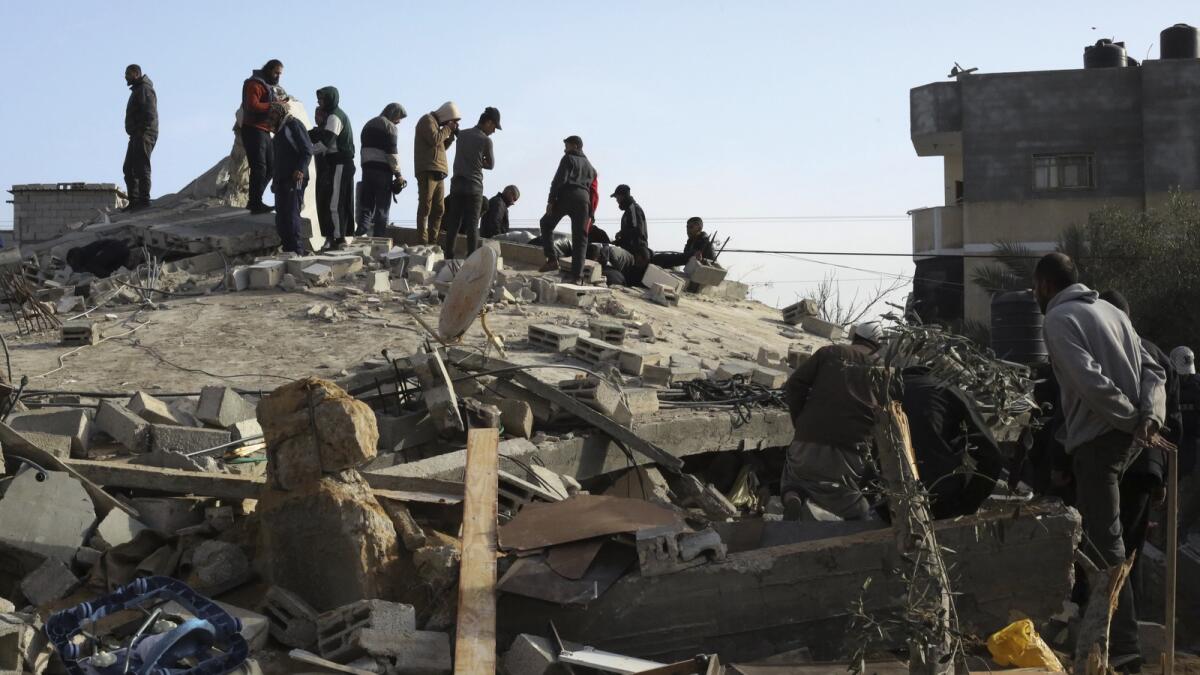 Palestinians look at the destruction after an Israeli strike on a residential building in Rafah. — AP