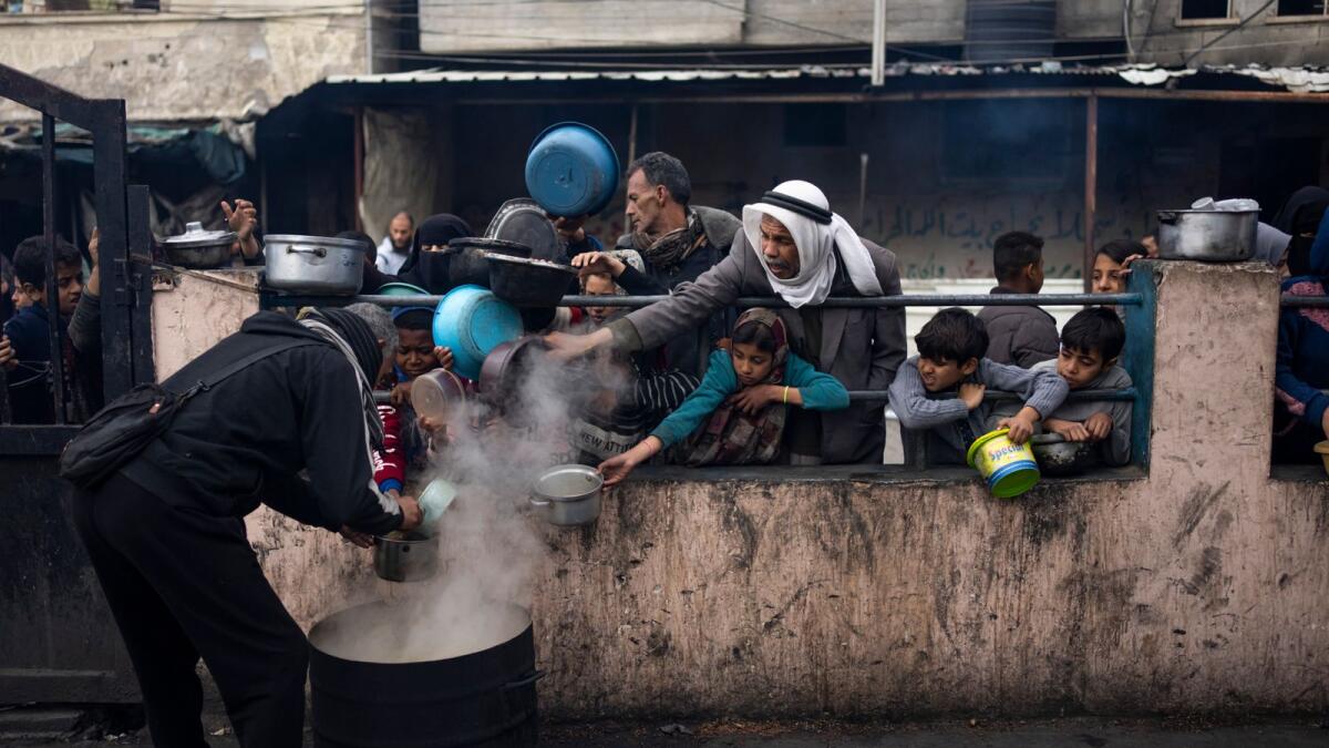 Palestinians line up for a free meal in Rafah. — AP