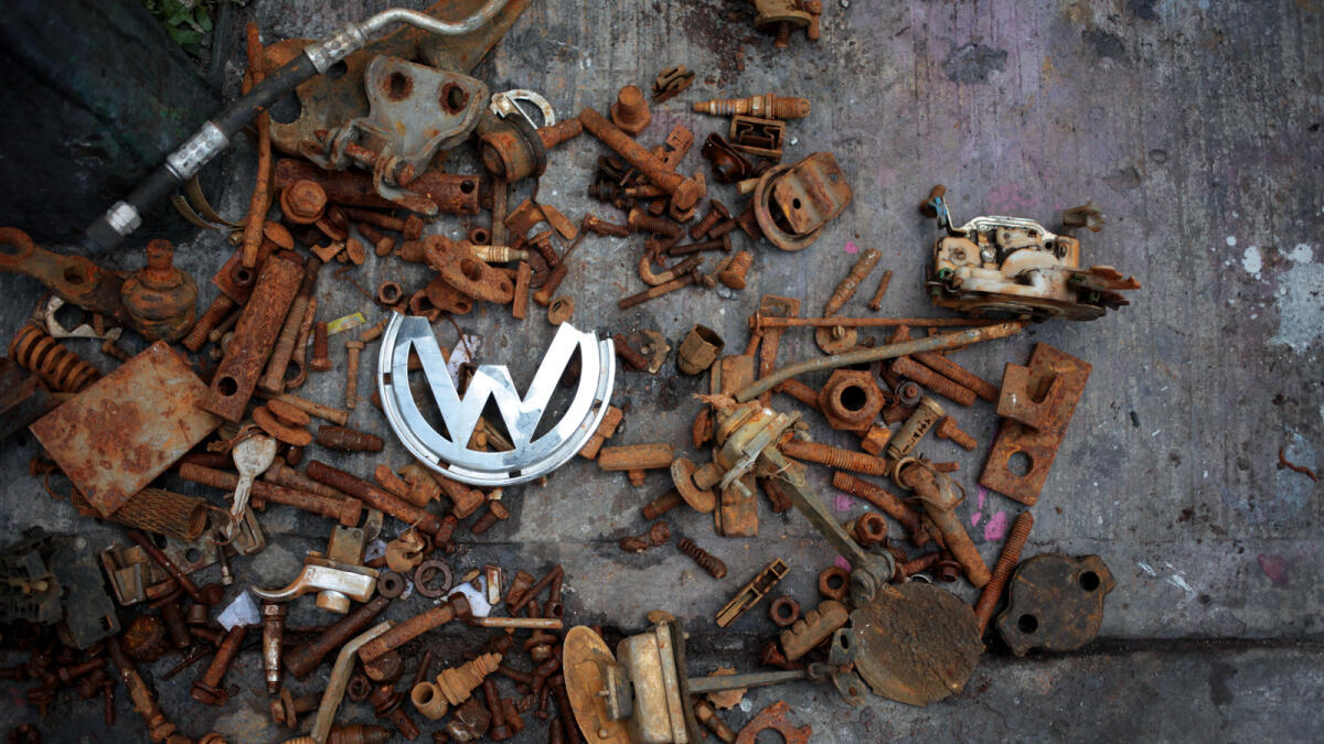 A broken Volkswagen logo lies among other rusted car parts at the scene where Armando Garcia and his father, Armando Aguilar, remodel Volkswagen beetles in Mexico City.