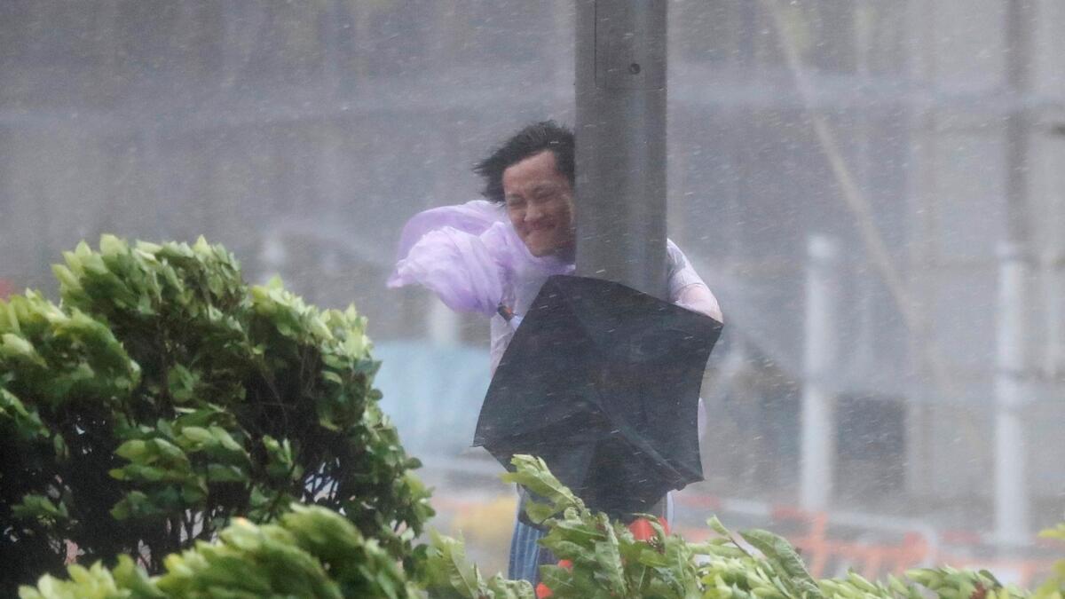 A man holds onto a lamp post against strong wind as typhoon hits China.