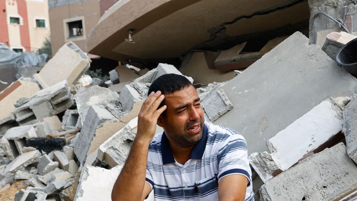 A Palestinian man reacts next to the ruins of a house destroyed in Israeli strikes in Khan Younis, in the southern Gaza Strip, October 8, 2023. Reuters