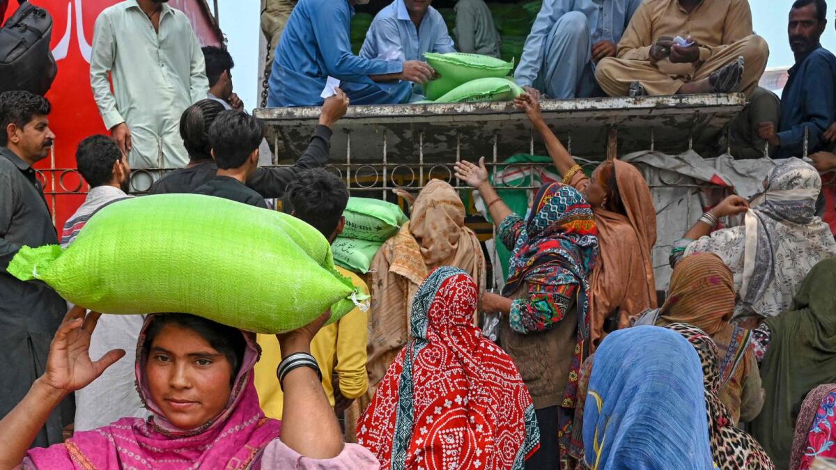 Women collect free bags of flour from a government distribution point in Lahore. — AFP