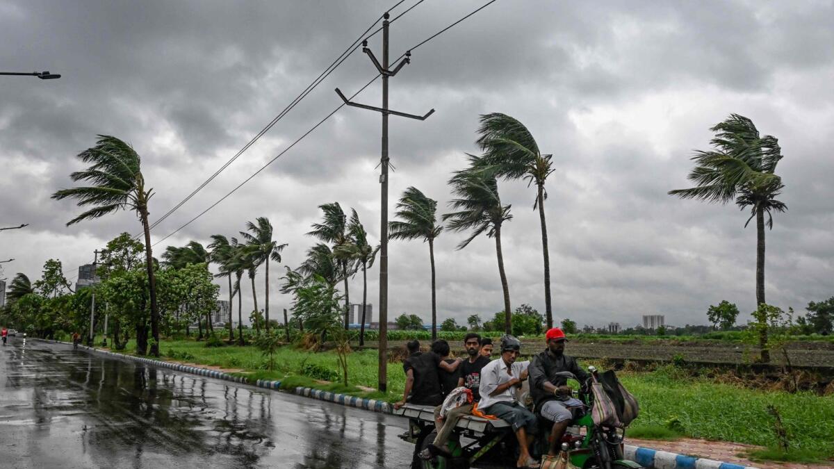 Commuters travel on a motorised three-wheeler along a road as rain clouds loom over the sky, due to the effect of cyclone Remal, in Kolkata. — Photo: AFP