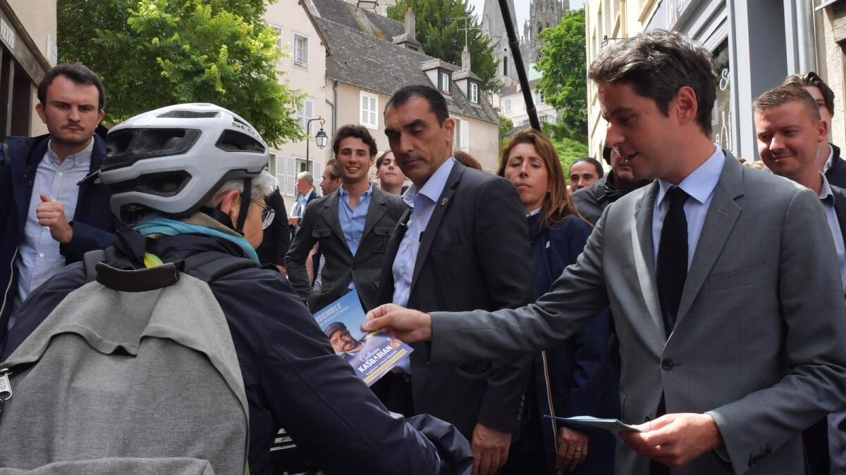 France's Prime Minister Gabriel Attal (R) distributes an election leaflet during a campaign visit in Chatres, centre France, on Tuesday, ahead of the second round of France's legislative elections.  AFP