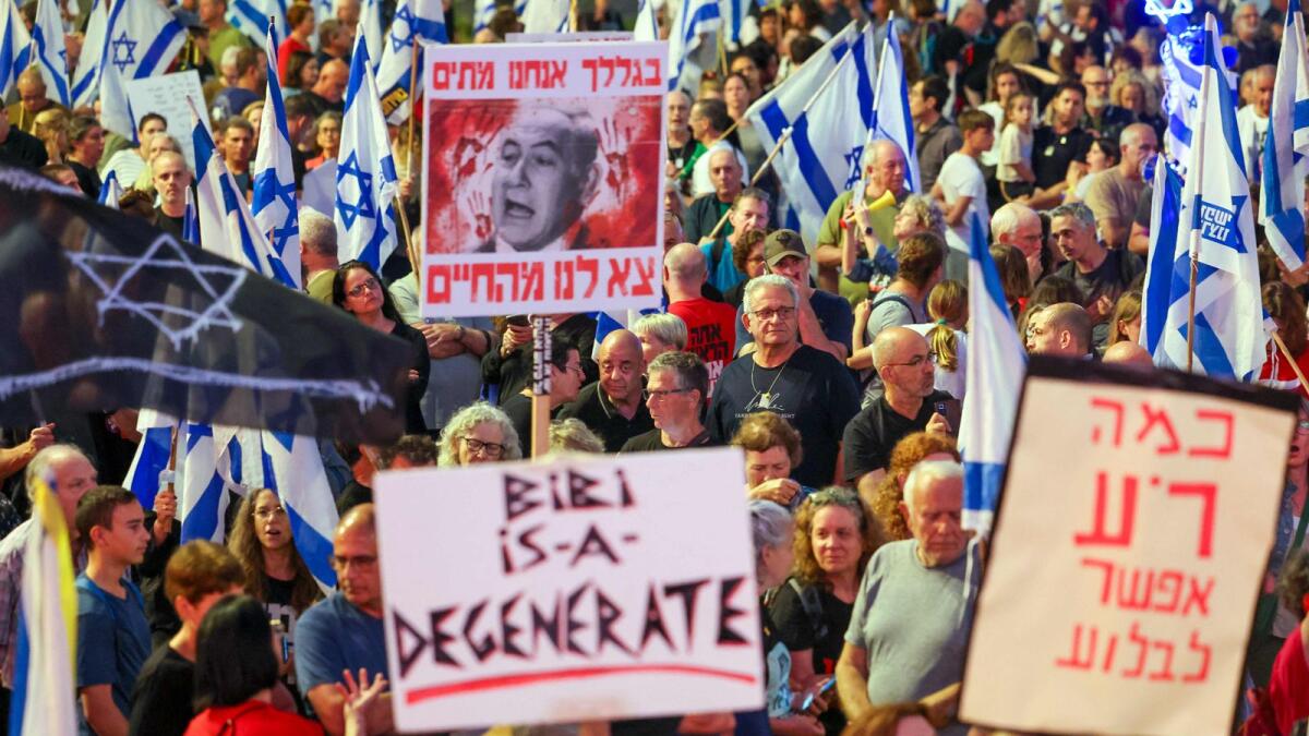 Protesters hold placards and wave national flags during an anti-government demonstration in Tel Aviv. Photo: AFP File