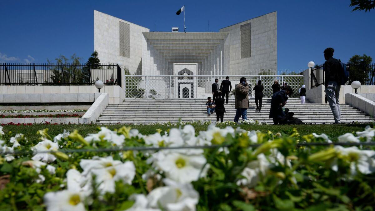 Lawyers and members of media gather outside the Supreme Court as they wait for court decision regarding provincial elections, in Islamabad, on Tuesday. — AP
