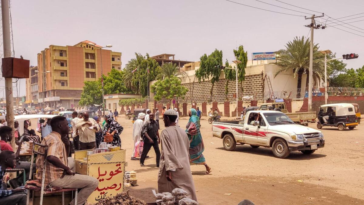 Pedestrians and vehicles move along a road outside a branch of the Central Bank of Sudan in the country's eastern city of Gedaref. Many civil servants in Sudan have been going on without a salary since the Sudanese army and the paramilitary Rapid Support Forces took up arms against each other. — AFP
