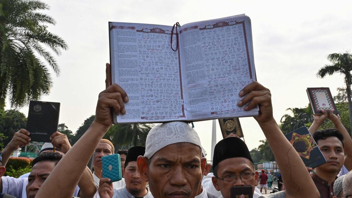 A demonstrator holds a copy of the Holy Quran with accompanying translation during a rally in Jakarta on Sunday, as they protest against the burning of the holy book outside a Stockholm mosque that outraged Muslims around the world.  — AP