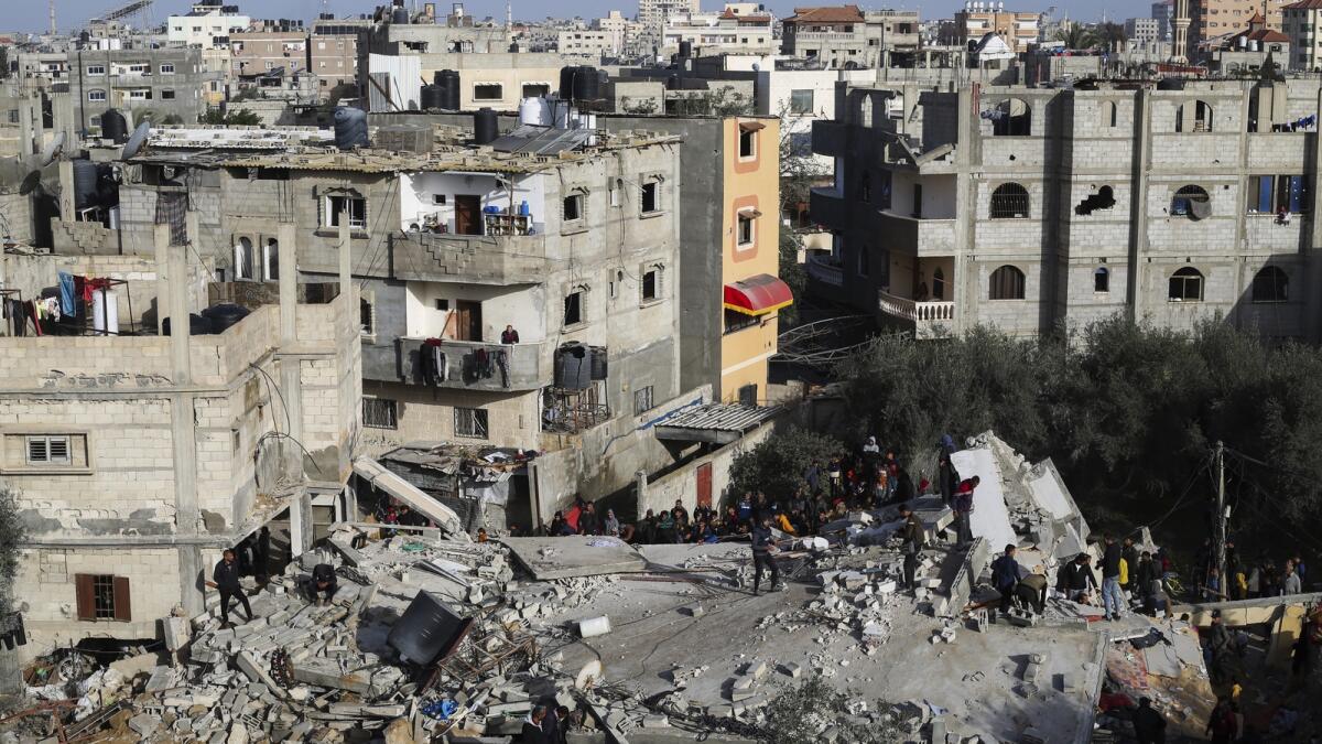 Palestinians look at the destruction after an Israeli strike on a residential building in Rafah. — AP