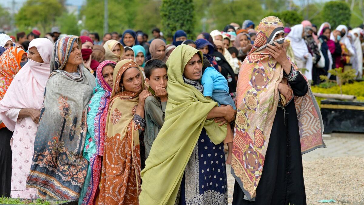 People queue to collect free bags of flour from a government distribution point in Islamabad on Saturday. —AFP