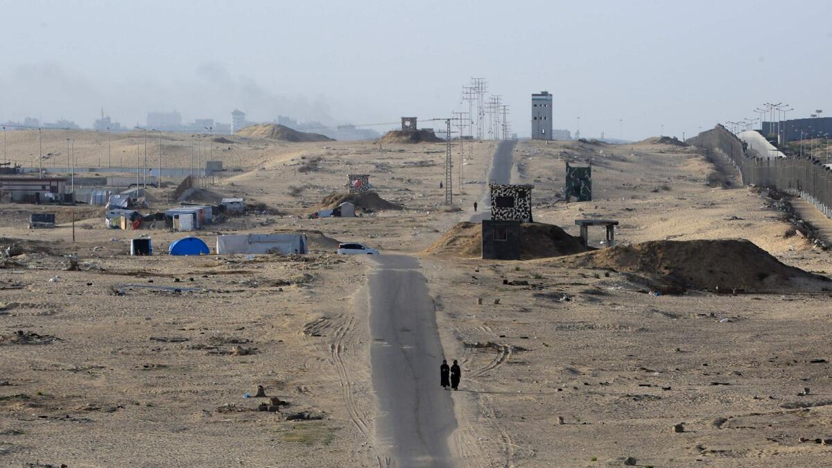 Two women walk on an asphalted road in the middle of a deserted camp for displaced Palestinians on the border with Egypt in Rafah. — Photo: AFP