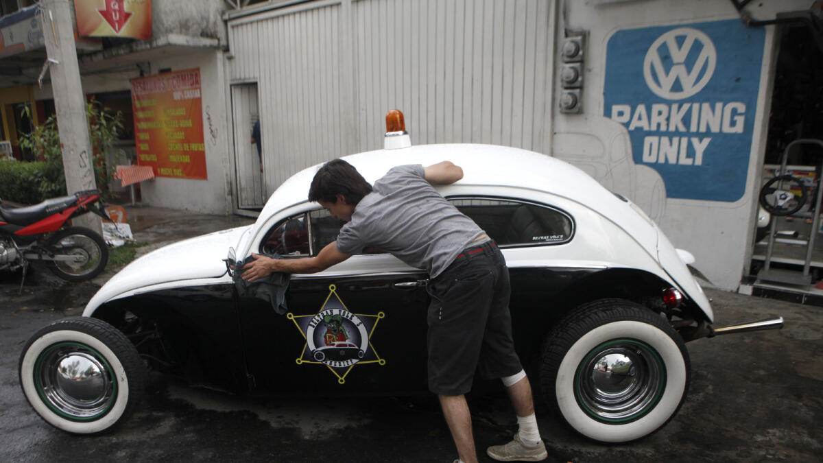 Dany Beltran polishes his 1956 Volkswagen beetle, named the Beltran Volk's Sheriff, outside of his family's Volkswagen repair and service shop in Mexico City.