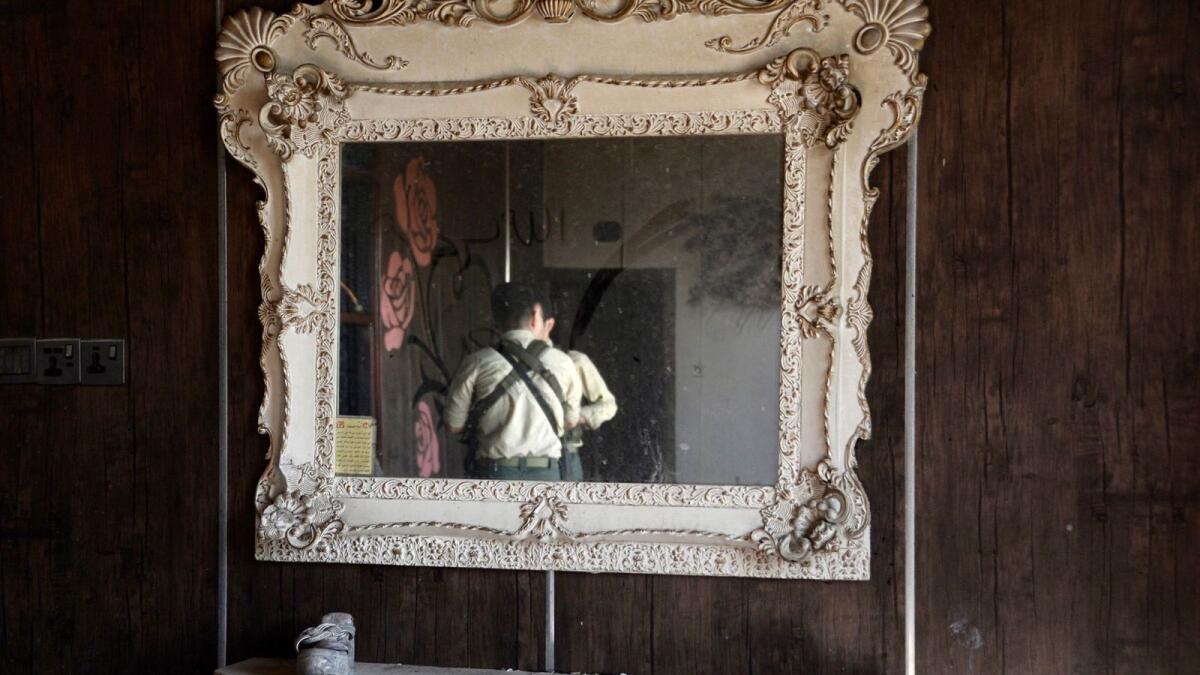The image of men inspecting the damage inside the Al-Haitham hall is reflected in an ornate mirror, days after a fire broke out during a wedding in Qaraqosh. — AFP file