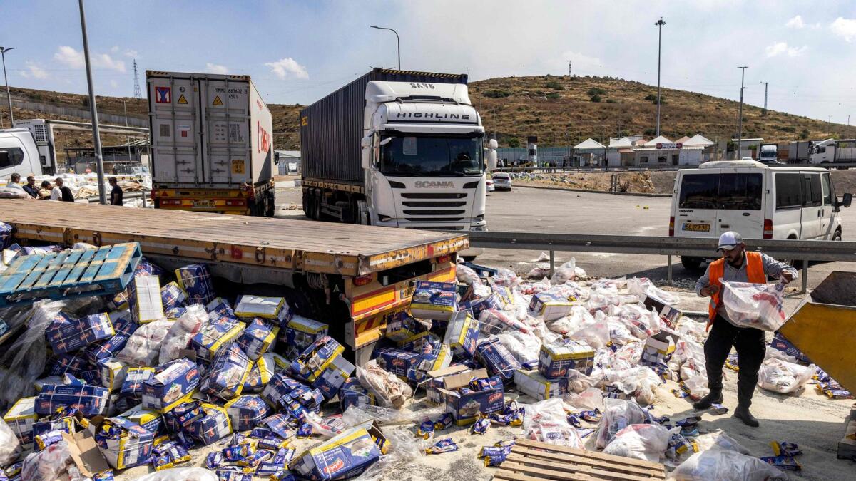 A worker clears humanitarian aid supplies spilled from damaged trucks on the Israeli side of the Tarqumiyah crossing with the occupied West Bank after they were vandalised by Israeli settlers. — Photo: AFP file