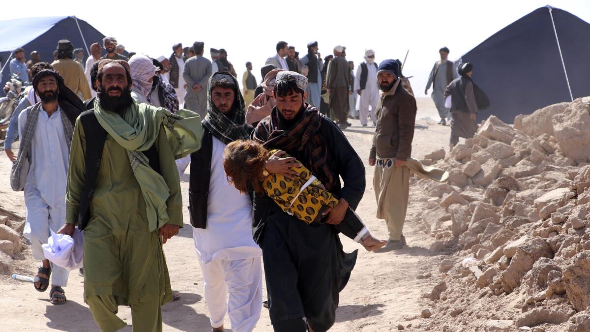 Afghans carry the body of a child after an earthquake in Zenda Jan district in Herat province. — AP