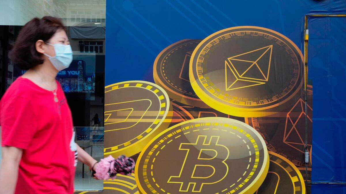 A woman walks past an advertisement for the Bitcoin cryptocurrency in Hong Kong.  Bitcoin once again fell below $17,000 on Saturday to an intraday low of $16,543.48, less than 24 hours after hitting a high of $17,480.18, when it was reported that a hack at FTX had taken place.  - AP