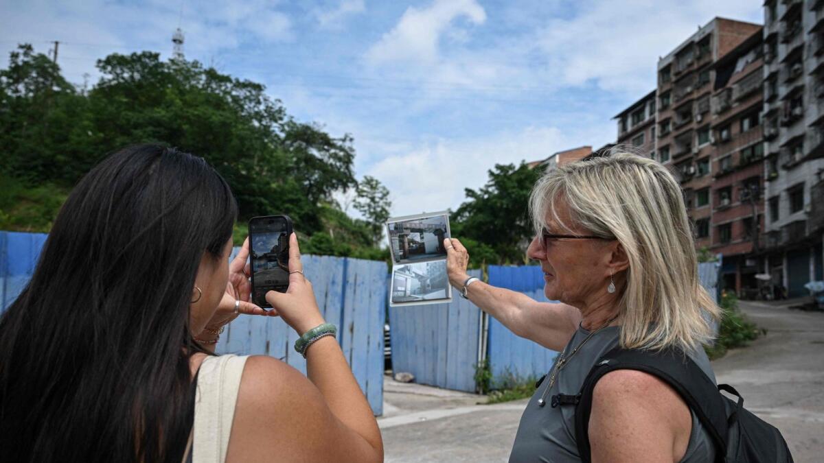 The photo taken on June 7, 2024 shows Loulee Wilson (L) taking a photo outside a now-demolished factory where Loulee believes she was found as a baby, in Dianjiang county, in southwestern China's Chongqing municipality.  AFP