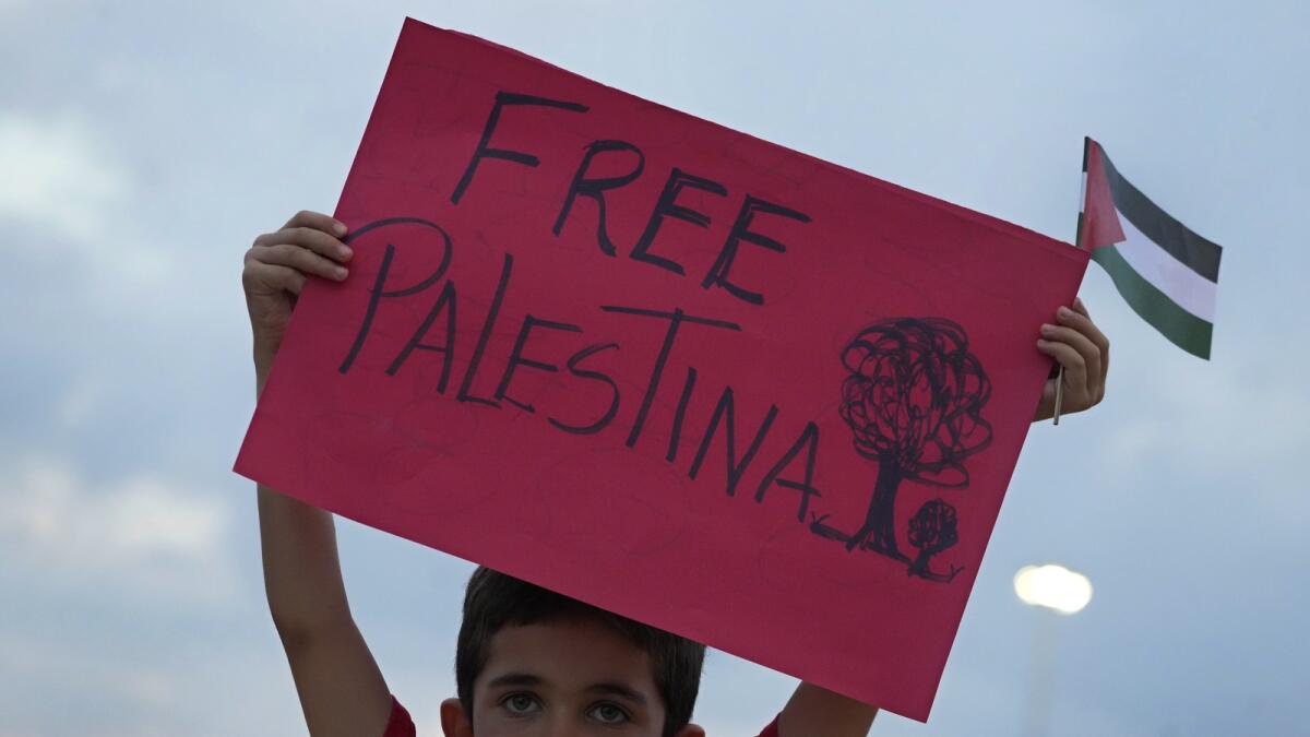 A boy from the Palestinian community shows a poster during Pro-Palestinian protest of the latest Israeli-Hamas war, outside the National Museum in Brasilia, Brazil. — AP