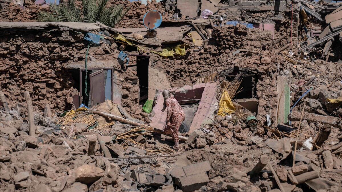A woman tries to recover some of her possessions from her home which was damaged by an earthquake in the village of Tafeghaghte, near Marrakech. — AP