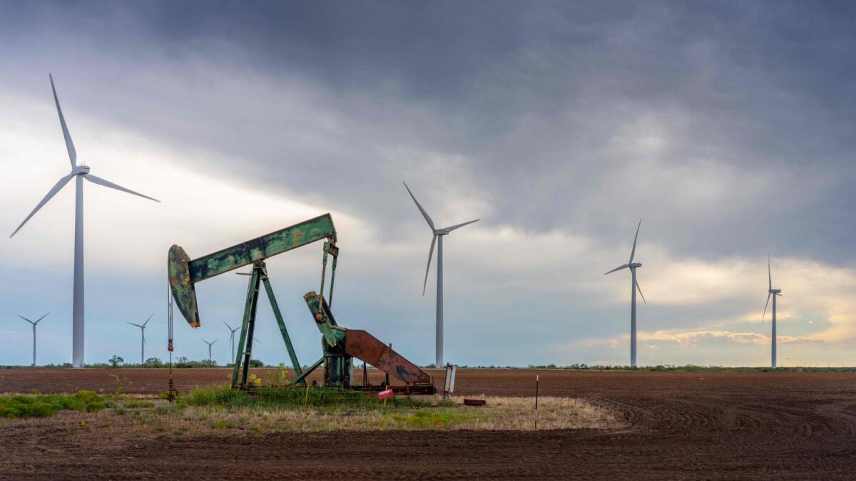 An oil pumpjack is seen near a field of wind turbines in Nolan, Texas. — AFP