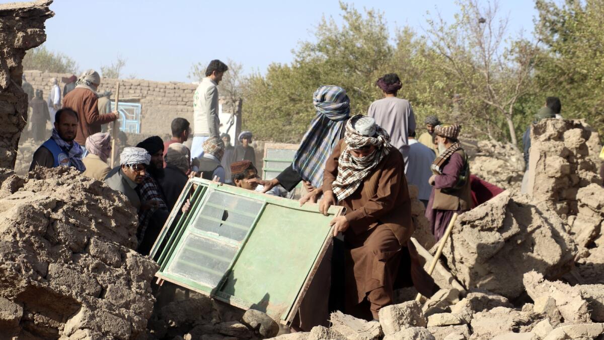 Afghan men remove debris after an earthquake in Zenda Jan district.