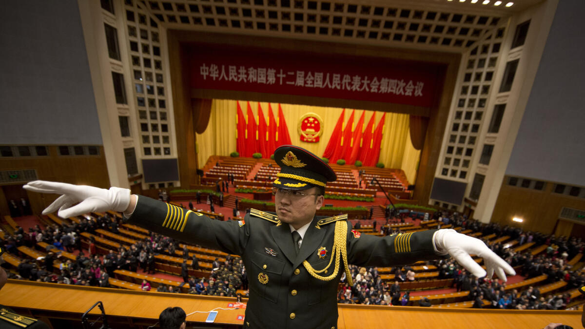 A Chinese military band conductor leads the band at the end of the opening session of the annual National People's Congress in Beijing's Great Hall of the People, Saturday, March 5, 2016. China?s leadership tried to quell anxiety about its slowing economy following financial turmoil and rising labor unrest as it cut its growth target Saturday and promised to open oil and telecoms industries to private competitors in sweeping industrial reforms. (AP Photo/Ng Han Guan)