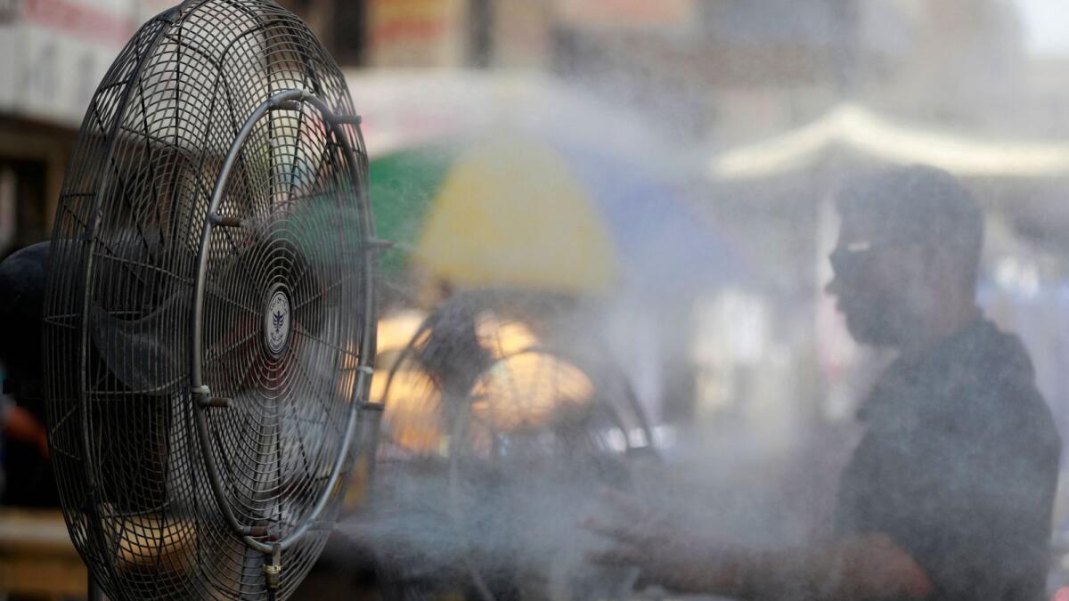 A man cools off with a mist dispenser set up on al-Jumhuriya street in central Baghdad amid soaring temperatures, on July 23, 2023. -- AP file
