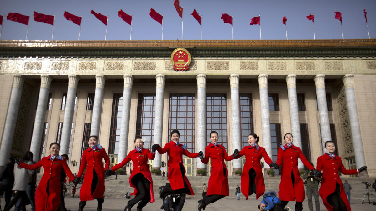 Hostesses, who facilitated the arrival of delegates by bus, leap as they pose for photographers in front of the Great Hall of the People during the opening session of China's annual National People's Congress (NPC) in Beijing, Saturday, March 5, 2016. (AP Photo/Mark Schiefelbein)