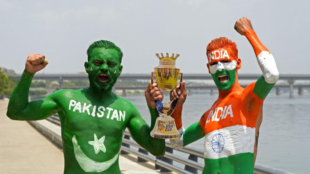 Fans with their bodies painted as national flags of India and Pakistan hold a cut-out of the Asia cup trophy, - AFP