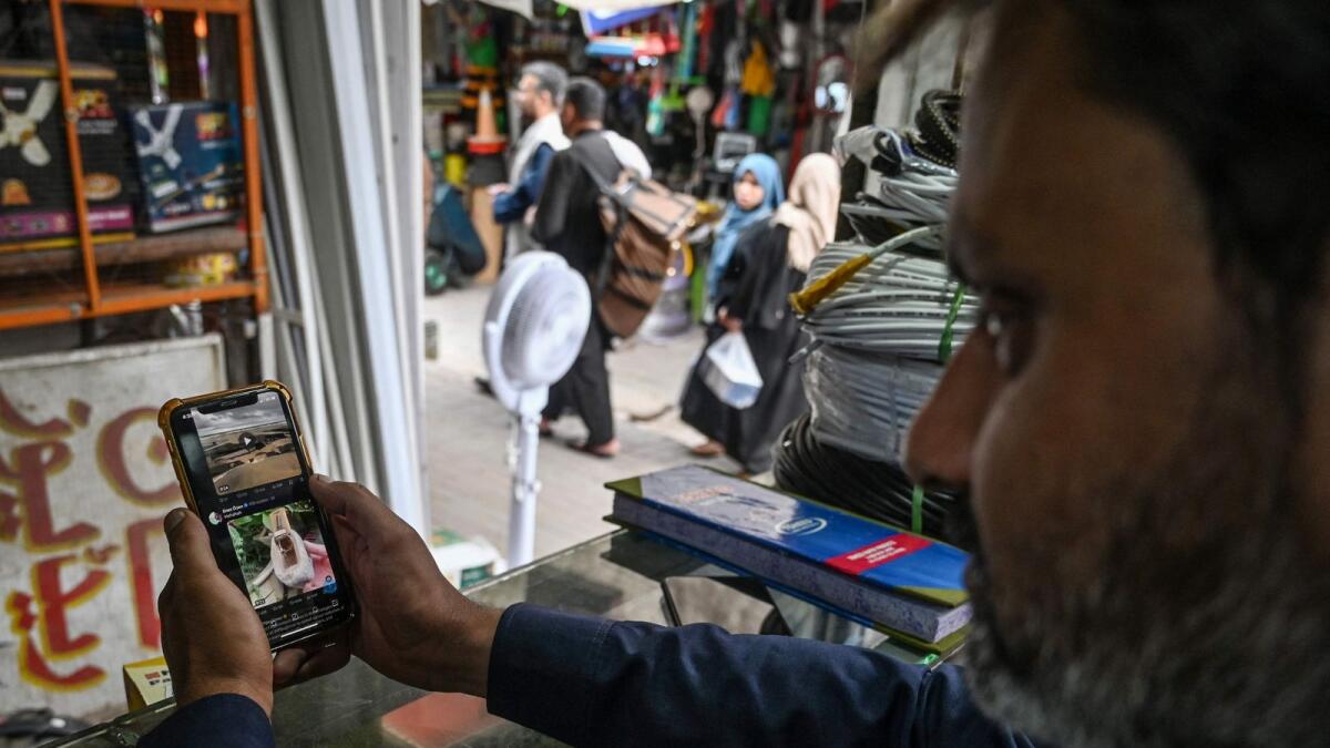 A man uses the social media platform X on his phone at a market in Islamabad. — AFP file