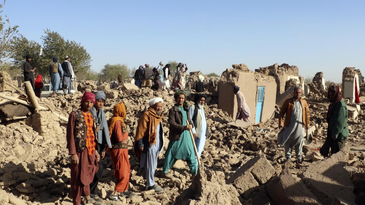 Afghans stand in a courtyard of their destroyed homes after an earthquake in Zenda Jan district in Herat province. — AP