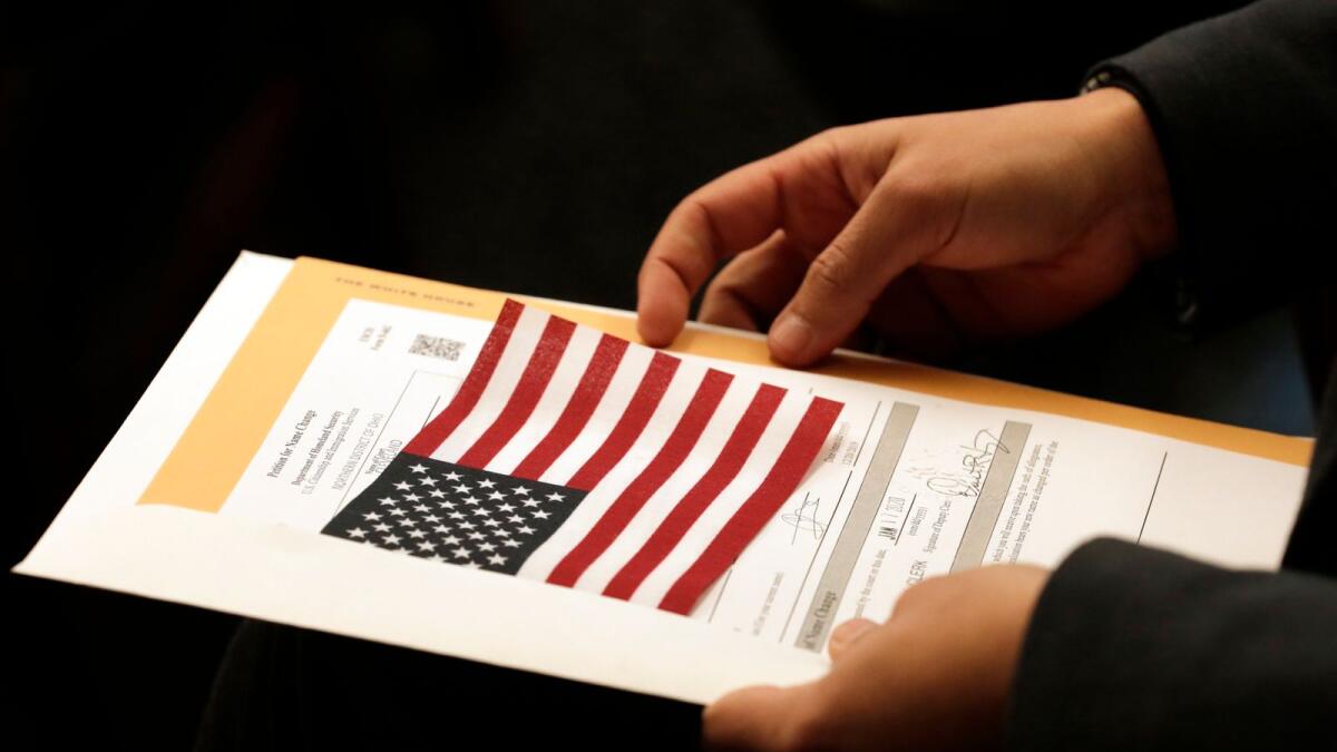 Abdullah Omar, from Iraq, holds his information packet and an American flag during a naturalization ceremony on Jan. 17, 2020, in Cleveland.  __ AP
