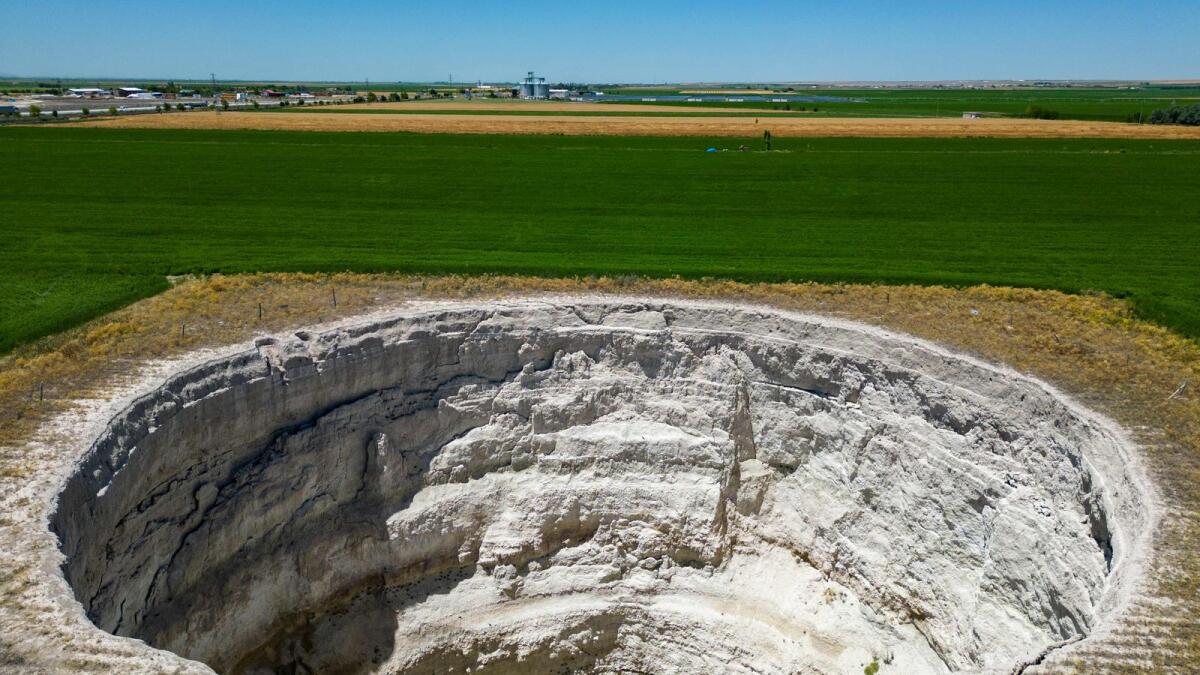 This aerial photograph shows a farmer walking around a giant sinkhole formed in the middle of the fields in Karapinar in the central Anatolian province of Konya. AFP