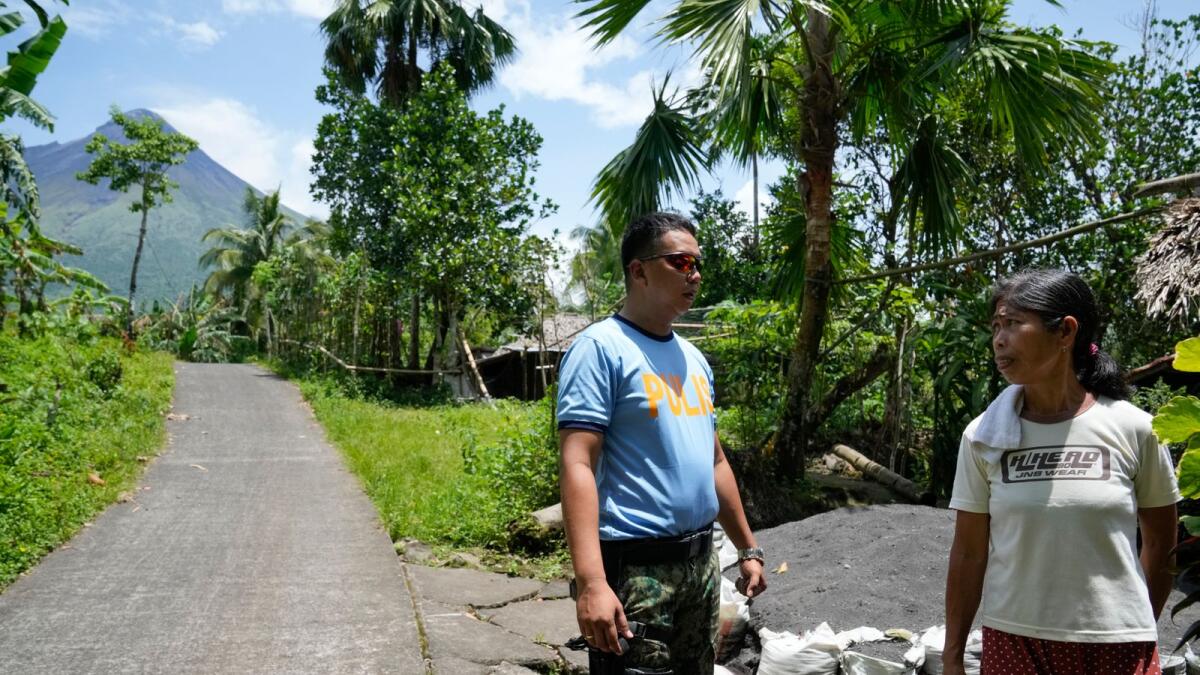 Delfina Guiwan, right, talks to police inside the government declared permanent danger zone surrounding Mayon volcano at Calbayog village, Albay province, northeastern Philippines.. AP