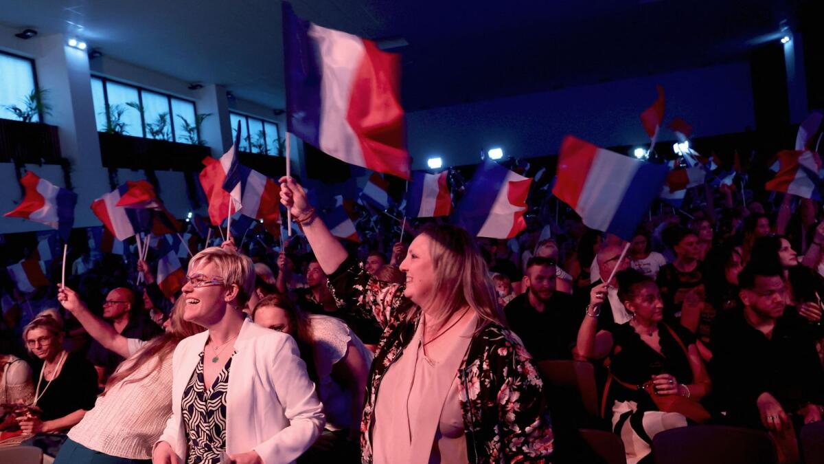 Supporters of Marine Le Pen, French far-right leader and far-right Rassemblement National (National Rally - RN) party candidate, hold French flags at the venue for Marine Le Pen's reaction speech before partial results in the first round of the early French parliamentary elections, in Henin-Beaumont, France, on Sunday. REUTERS