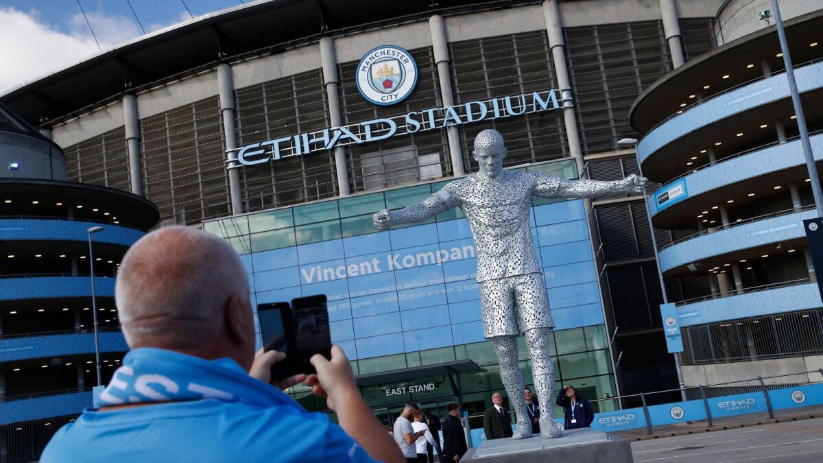 A Manchester City fan taking a picture of a statue of former player and captain Vincent Kompany outside the stadium. — Reuters