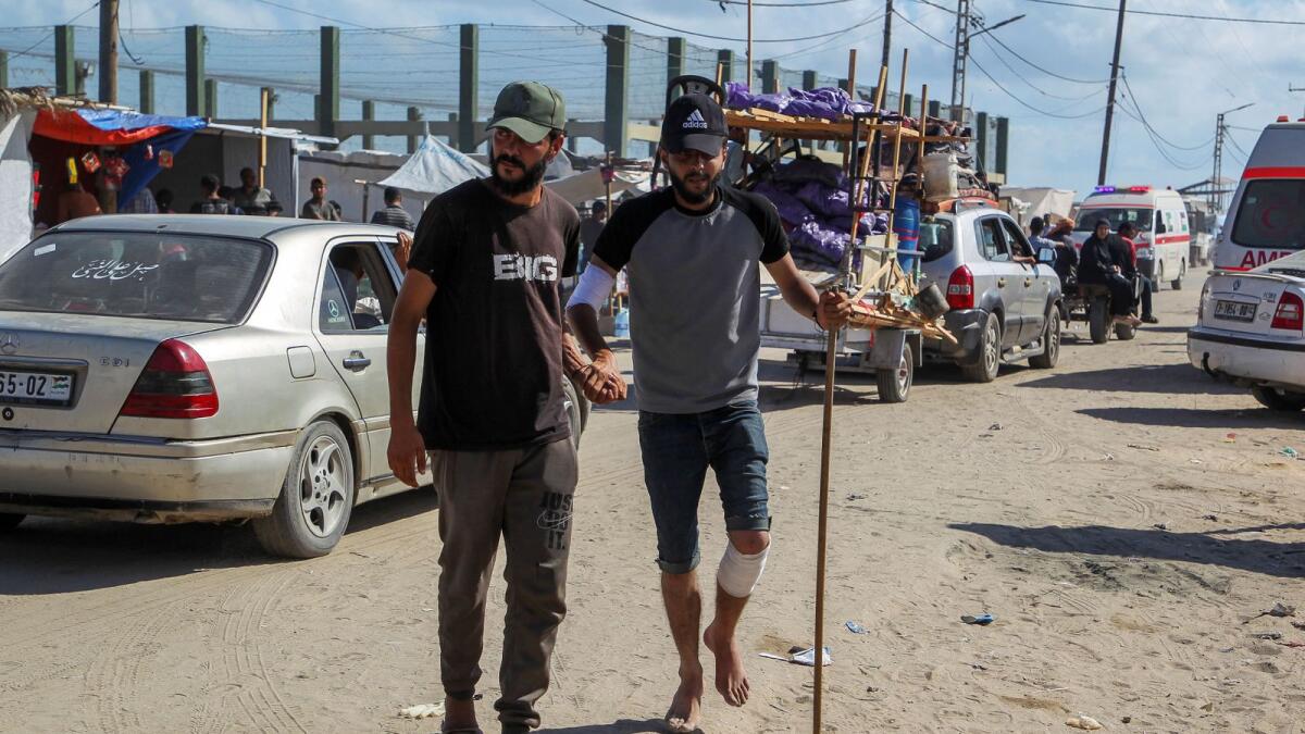 A Palestinian man wounded in an Israeli strike is helped as he walks outside a field hospital where he receives treatment, in Rafah. — Photo: Reuters