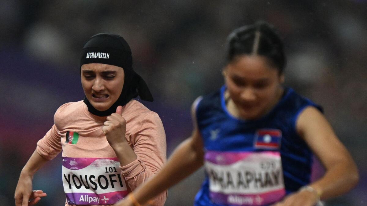 Kimia Yousofi (L) competes in the women's 100m heats athletics event in Hangzhou. — AFP