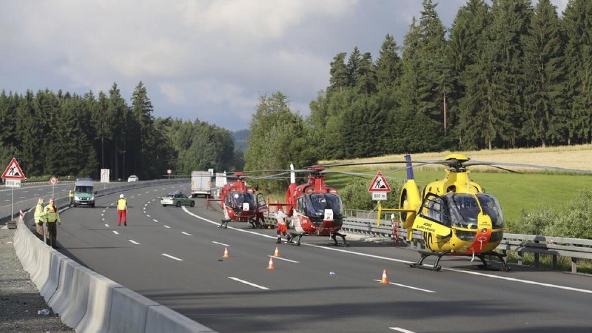 Rescue helicopters stand on the motorway after the bus burst into flames